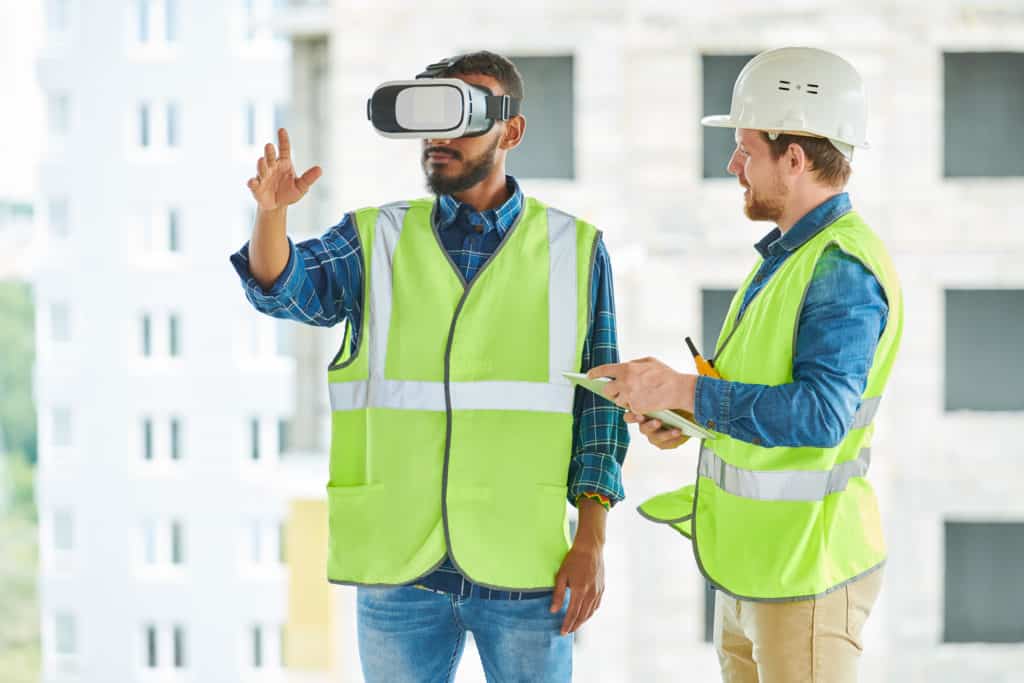 Waist up portrait of two modern construction workers using VR gear to visualize projects  on site, copy space