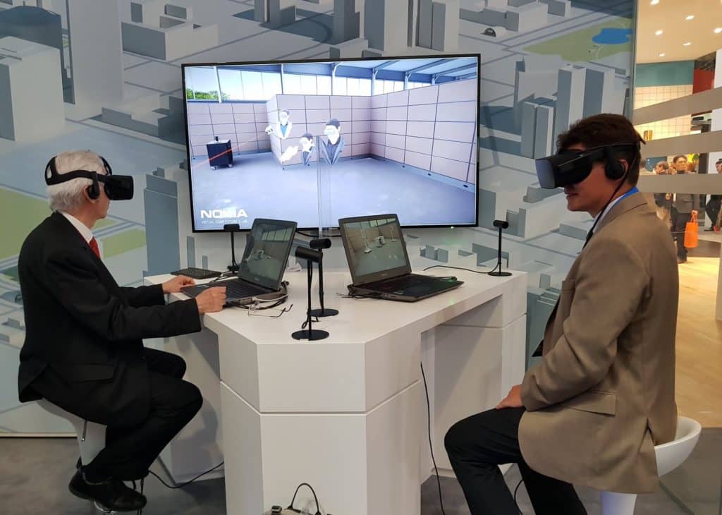 Ihmiset VR-lasit päässä tietokoneruutujen edessä.