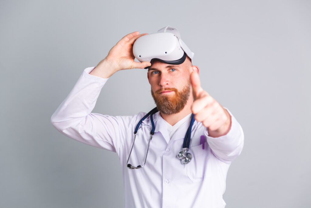 Handsome male doctor on gray background in virtual reality glasses